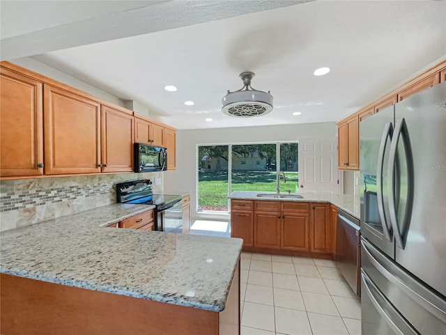 kitchen featuring light tile patterned floors, a sink, light stone countertops, black appliances, and backsplash