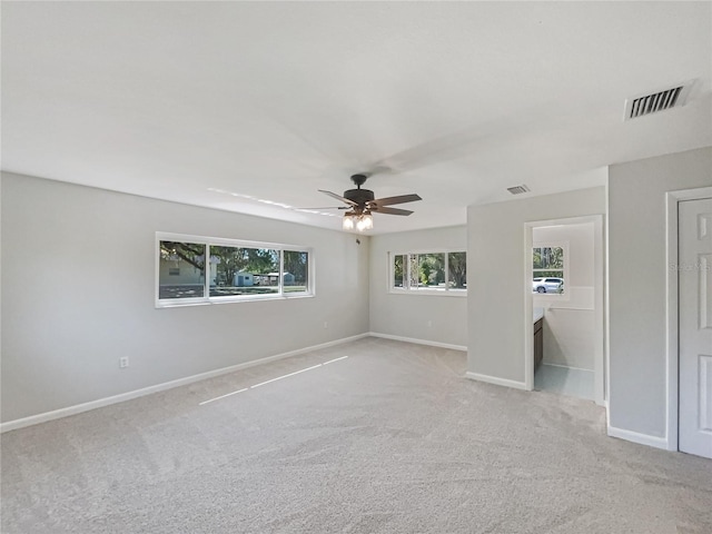 spare room with baseboards, visible vents, a ceiling fan, and light colored carpet