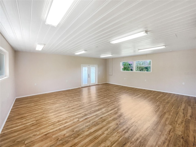 unfurnished room featuring french doors, baseboards, and wood finished floors