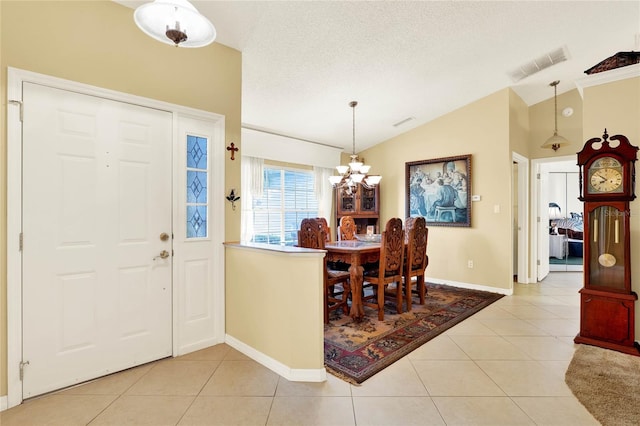 foyer entrance featuring lofted ceiling, light tile patterned floors, a textured ceiling, and visible vents