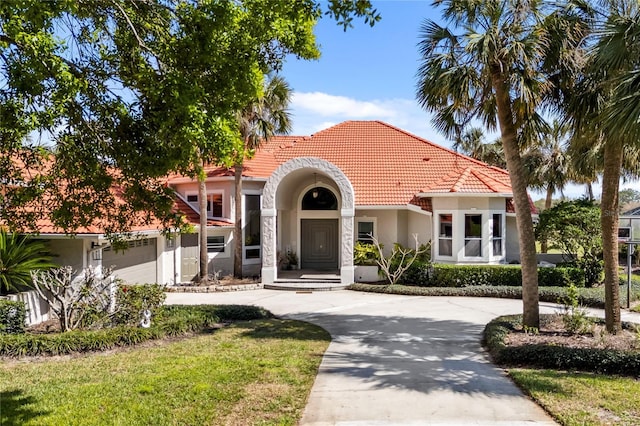 mediterranean / spanish-style home featuring a garage, a tile roof, concrete driveway, and stucco siding