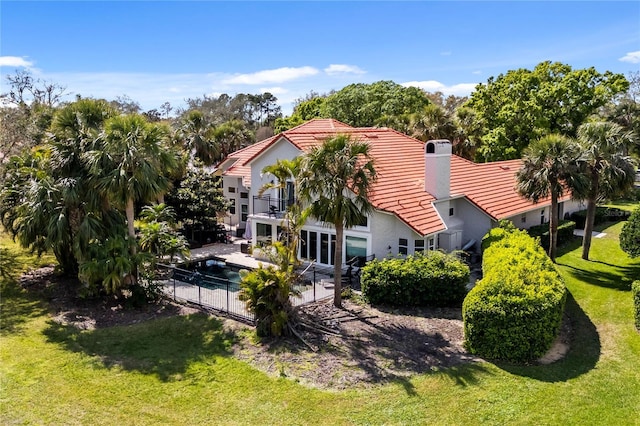 rear view of property featuring a lawn, a patio, a balcony, a tile roof, and fence