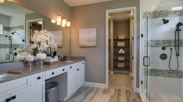 full bath with baseboards, double vanity, a sink, and a shower stall