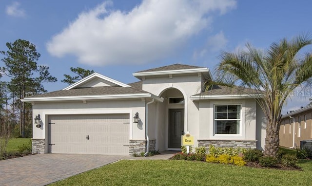 view of front facade with decorative driveway, stucco siding, an attached garage, a front yard, and stone siding