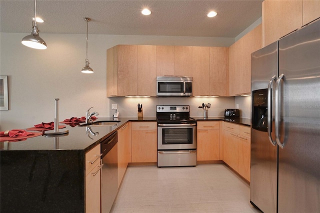 kitchen featuring decorative light fixtures, stainless steel appliances, light brown cabinets, a sink, and a peninsula
