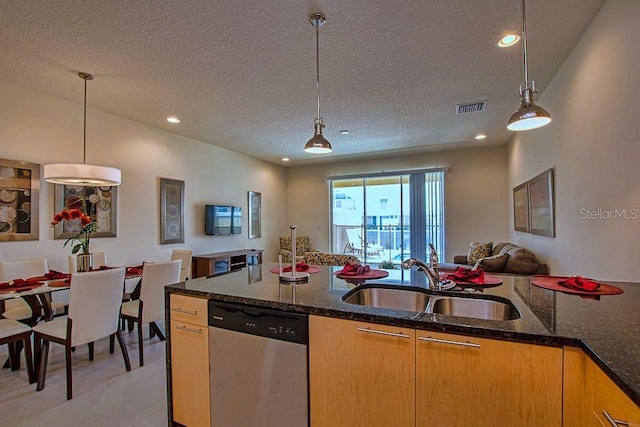 kitchen featuring a sink, dark stone countertops, open floor plan, and dishwasher