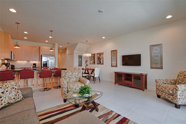 living area with light tile patterned floors, baseboards, a textured ceiling, and recessed lighting