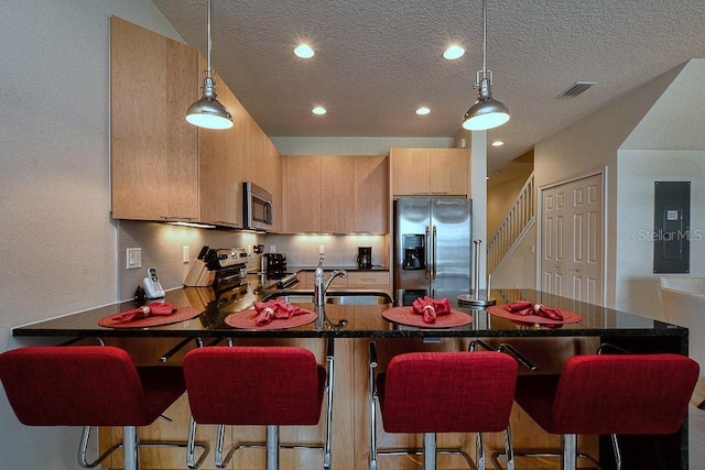 kitchen with decorative light fixtures, recessed lighting, visible vents, appliances with stainless steel finishes, and a peninsula
