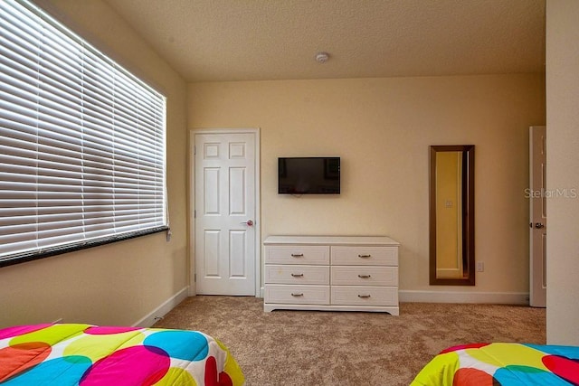 bedroom with light carpet, baseboards, and a textured ceiling