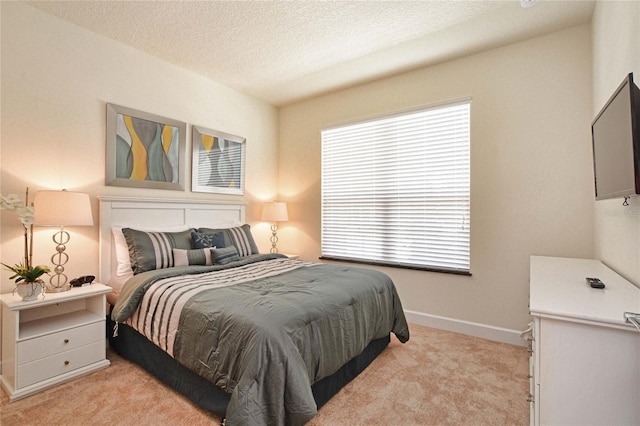 bedroom featuring light colored carpet, a textured ceiling, baseboards, and multiple windows