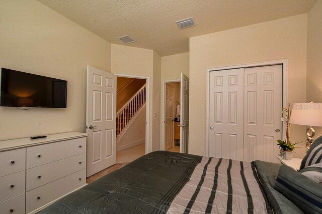 bedroom with a textured ceiling, visible vents, and a closet