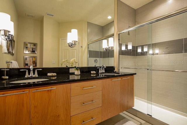 bathroom with a stall shower, visible vents, and a sink