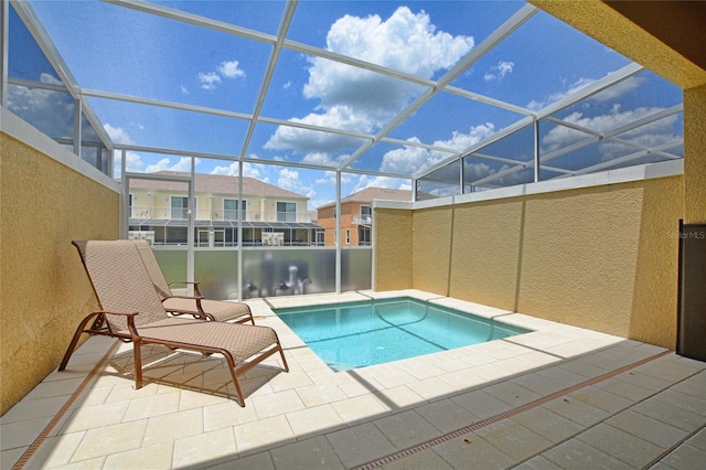 outdoor pool with glass enclosure and a patio area