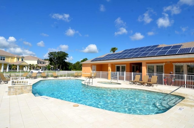community pool with a patio area, a hot tub, and fence