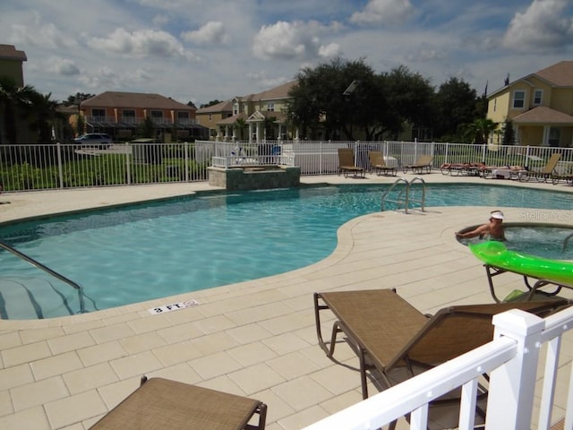 view of swimming pool featuring a patio area, fence, and a residential view