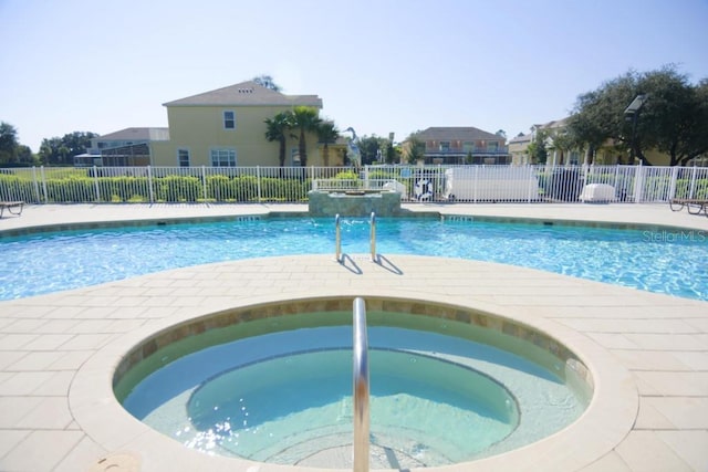 pool with a patio area, a hot tub, and fence