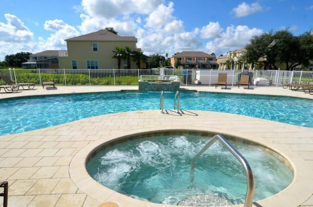 pool with a community hot tub, fence, a residential view, and a patio