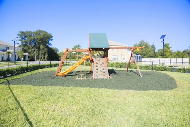 community play area featuring a lawn and fence