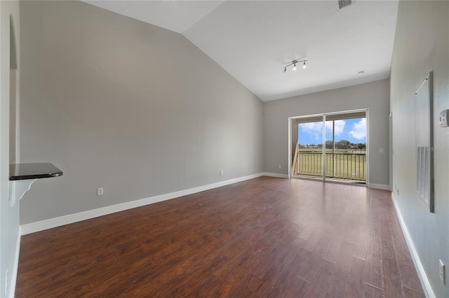 spare room featuring lofted ceiling, visible vents, baseboards, and wood finished floors