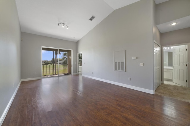 empty room featuring high vaulted ceiling, baseboards, visible vents, and wood finished floors