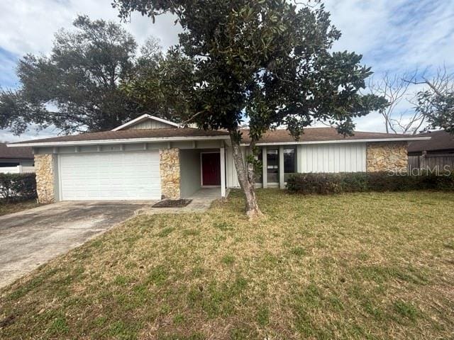 single story home featuring a garage, stone siding, driveway, and a front lawn