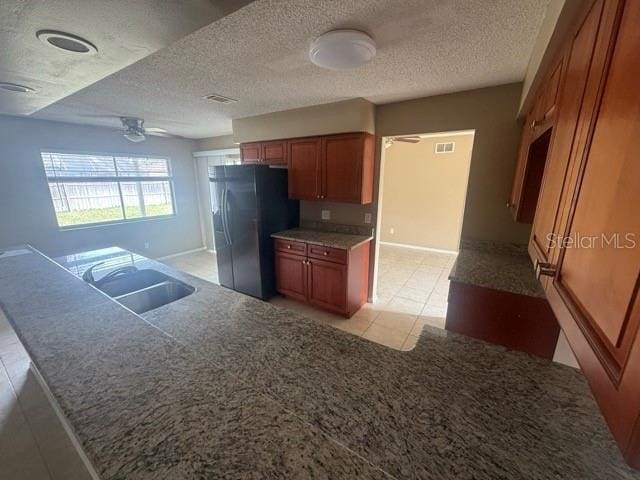 kitchen featuring visible vents, a ceiling fan, brown cabinets, fridge with ice dispenser, and a sink