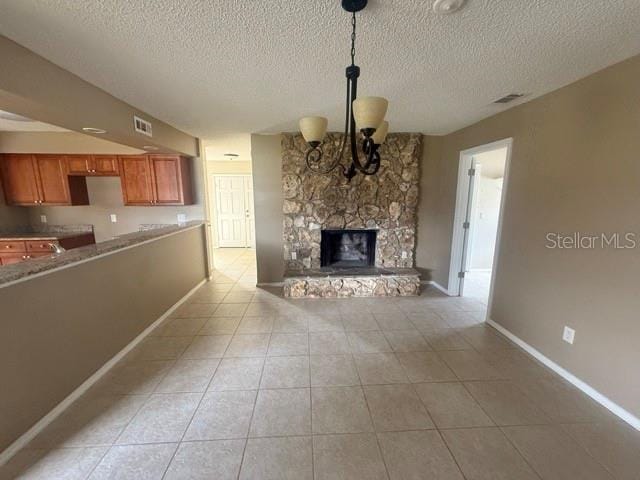 unfurnished living room featuring light tile patterned floors, a fireplace, visible vents, and a notable chandelier