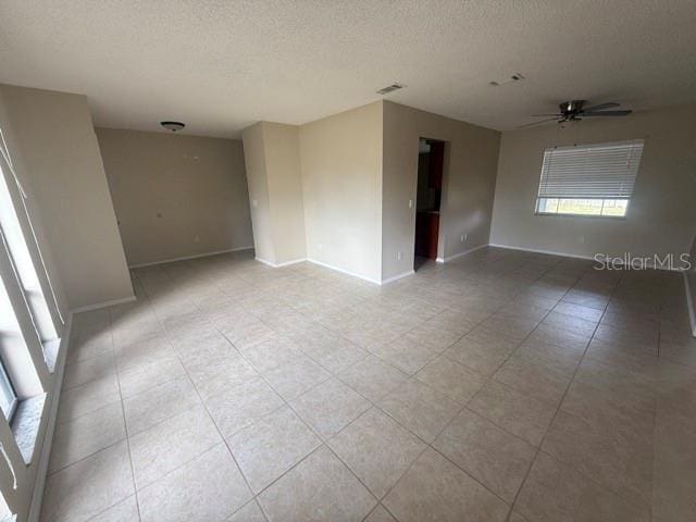 empty room featuring visible vents, ceiling fan, a textured ceiling, and baseboards