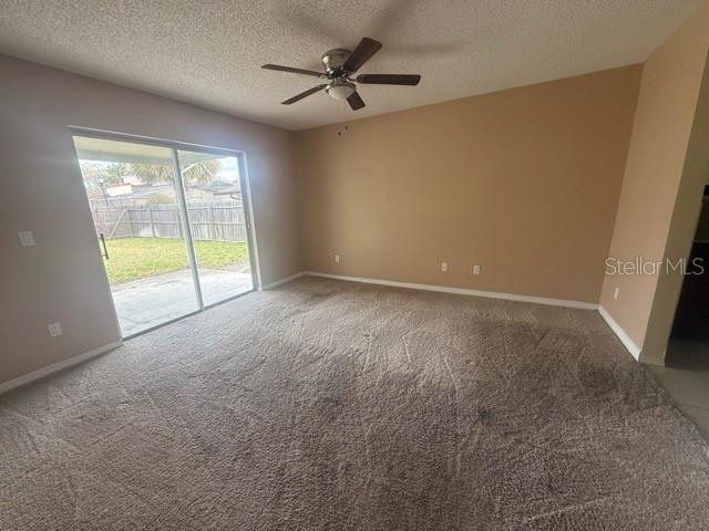 spare room featuring ceiling fan, a textured ceiling, carpet, and baseboards