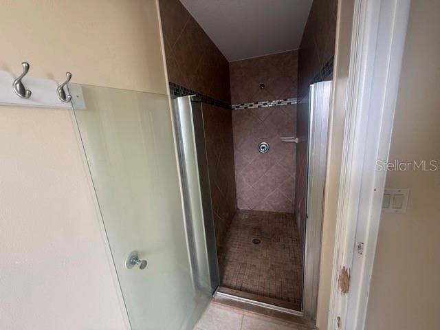 full bathroom with tiled shower and tile patterned floors