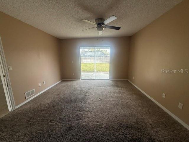 carpeted spare room with ceiling fan, visible vents, baseboards, and a textured ceiling