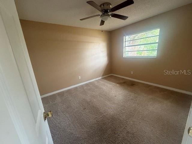 carpeted empty room featuring a ceiling fan, baseboards, and a textured ceiling