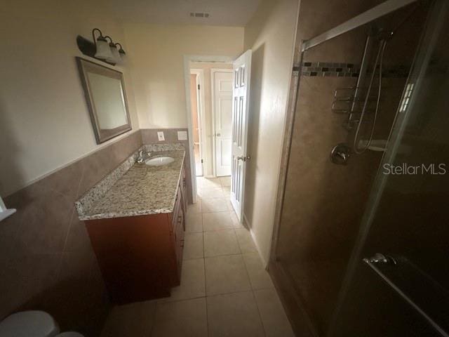 full bathroom with a stall shower, visible vents, tile patterned flooring, vanity, and tile walls