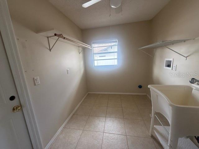 washroom featuring laundry area, light tile patterned floors, baseboards, hookup for a washing machine, and a textured ceiling