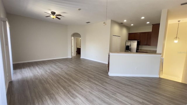 unfurnished living room with baseboards, arched walkways, ceiling fan, wood finished floors, and recessed lighting