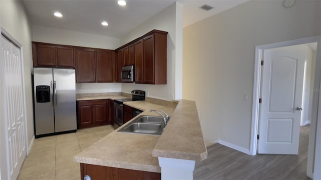 kitchen with visible vents, appliances with stainless steel finishes, a peninsula, light countertops, and a sink