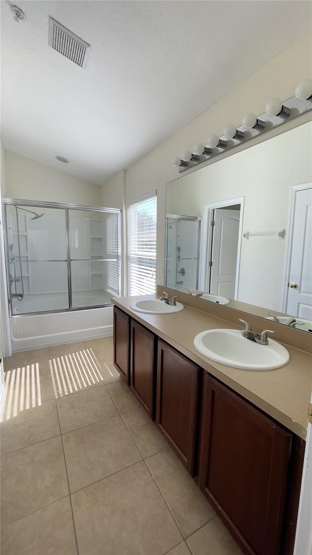 full bath with tile patterned flooring, shower / bath combination with glass door, visible vents, and a sink