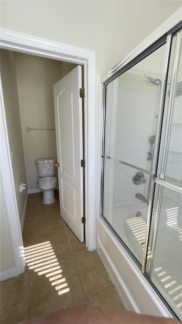 bathroom with enclosed tub / shower combo, tile patterned flooring, toilet, and baseboards