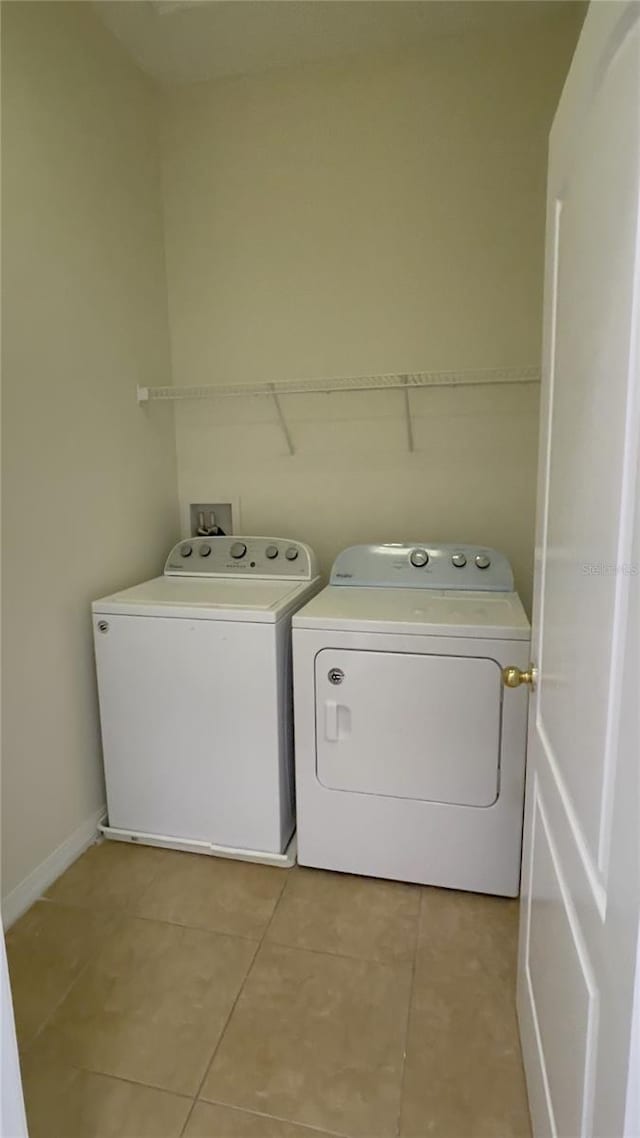 washroom featuring laundry area, light tile patterned flooring, independent washer and dryer, and baseboards