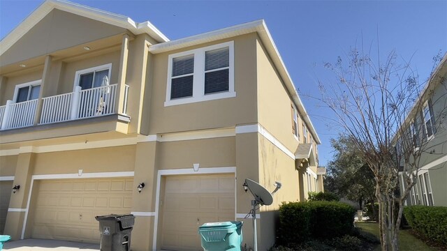 view of property exterior featuring a garage, a balcony, and stucco siding