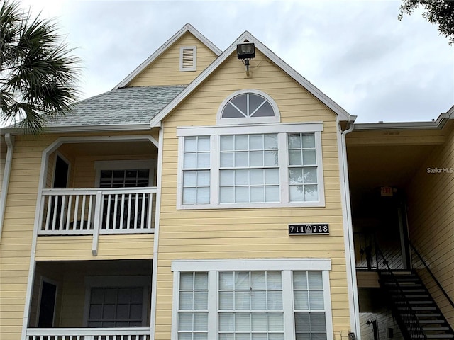 view of home's exterior featuring a shingled roof and a balcony