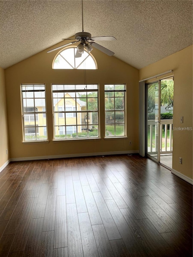 spare room with dark wood-style floors, vaulted ceiling, and plenty of natural light