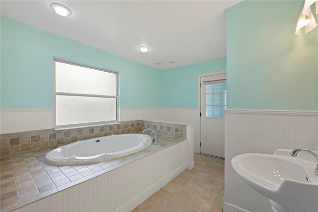 1111 Guernsey St, Orlando, FL 32804 - bathroom with a garden tub, tile patterned flooring, wainscoting, and a sink