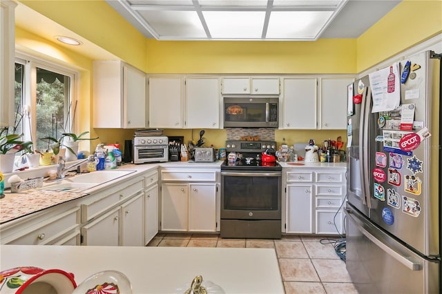 kitchen featuring a sink, appliances with stainless steel finishes, light tile patterned flooring, and light countertops