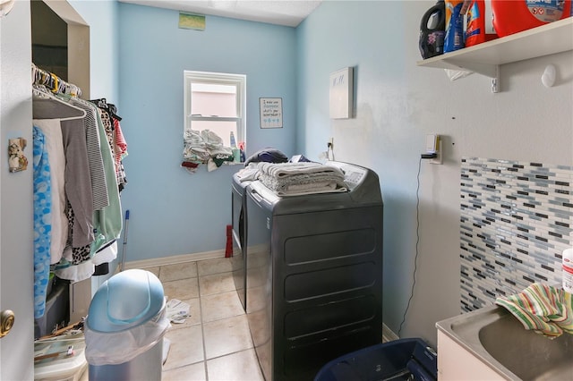 laundry room with baseboards, laundry area, a sink, tile patterned flooring, and independent washer and dryer