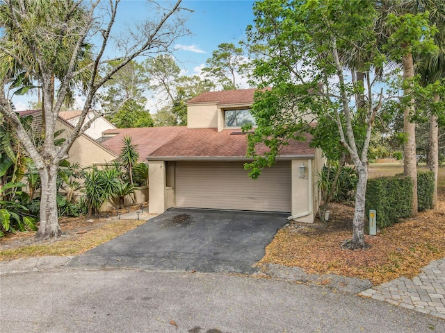 view of front of property with aphalt driveway, roof with shingles, and stucco siding