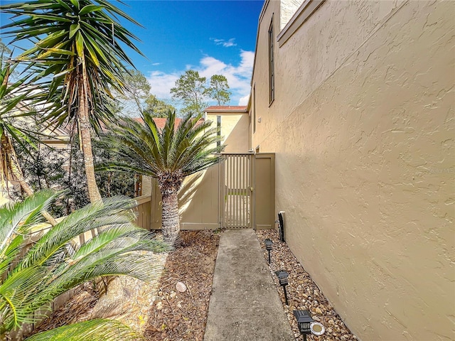 view of property exterior featuring a gate, fence, and stucco siding