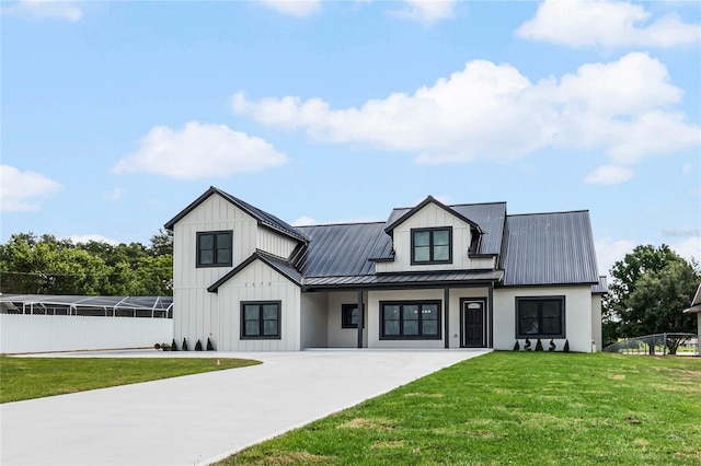 modern farmhouse style home featuring metal roof, fence, board and batten siding, a front lawn, and a standing seam roof