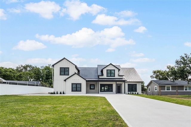 modern farmhouse style home with metal roof, a standing seam roof, fence, board and batten siding, and a front yard