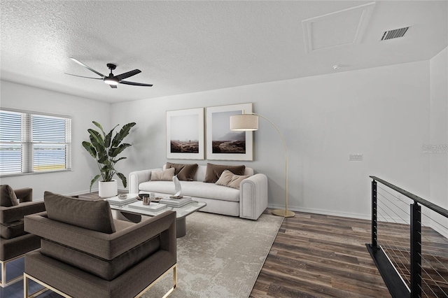 living room featuring visible vents, a ceiling fan, a textured ceiling, wood finished floors, and baseboards